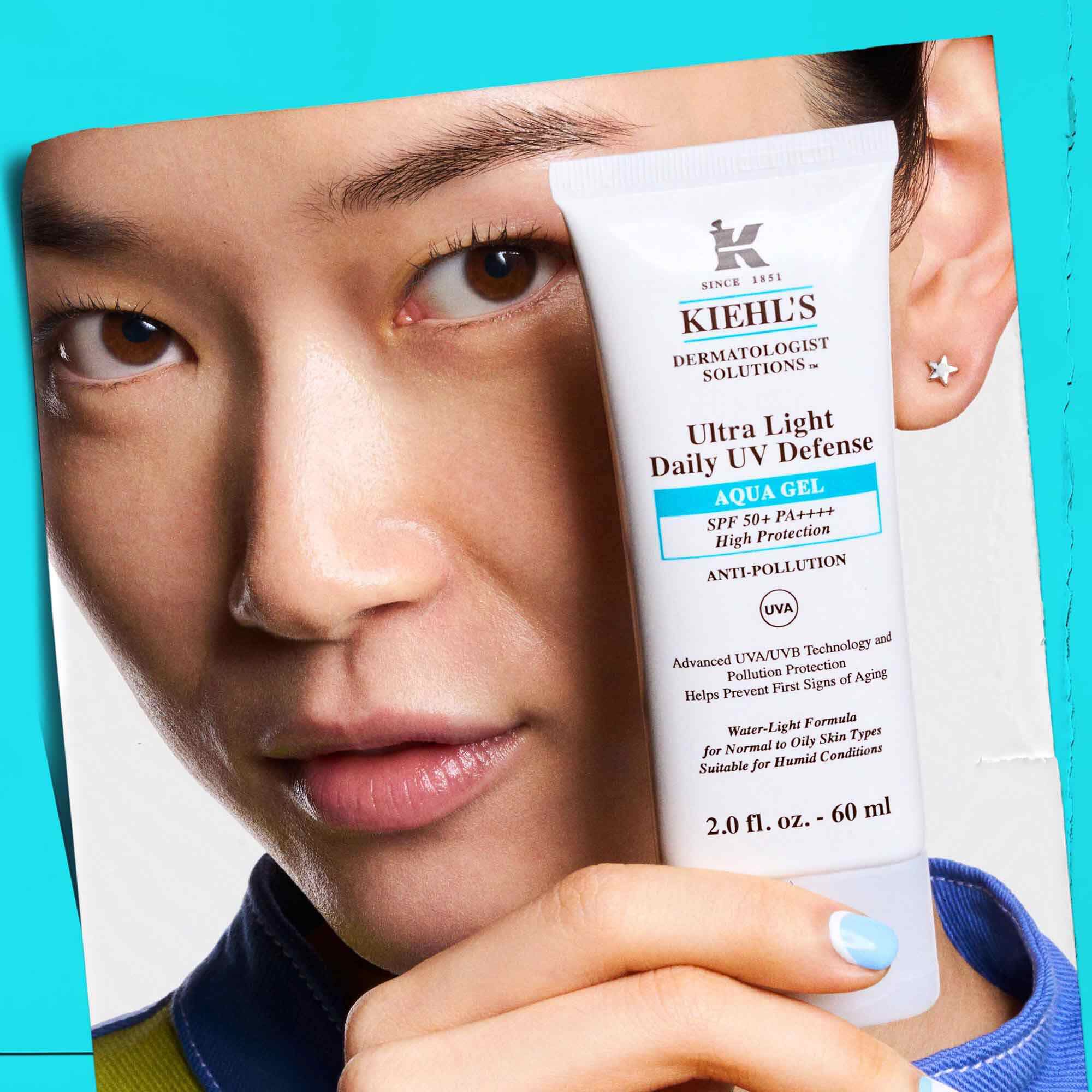 Ein Model halt eine Tube Ultra Light Daily UV Defense Aqua Gel, was die Tragbarkeit und einfache Anwendung zeigt.