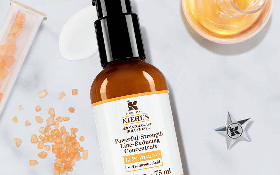 Alt-Text: Eine minimalistische Anordnung von Hautpflegeprodukten auf einer marmorierten Oberflache, einschließlich einer Flasche mit Serum und einer Flasche mit Feuchtigkeitscreme, umgeben von verschiedenen Inhaltsstoffen wie Kristallen und Olen.