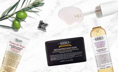 Produktauswahl von Kiehl's: Korperseife, volumengebendes Shampoo, Lotion und Olivenzweig als Dekoration.