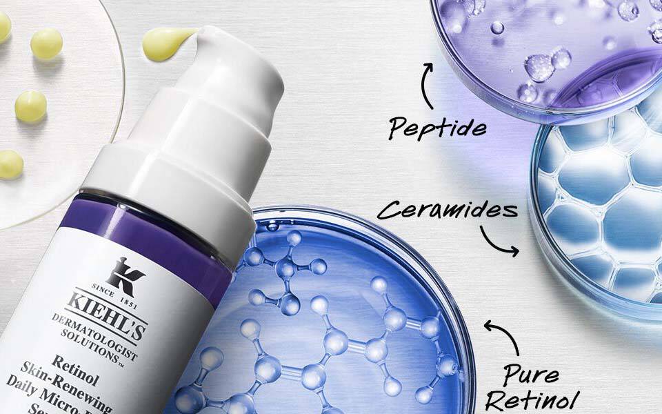 Ein Grauflache mit verschiedenen Hautpflegeprodukten, darunter eine Pumpflasche und mehrere Glaser mit verschiedenen Texturen in Blau und Lila.