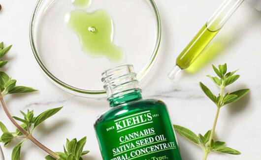 Bild zeigt verschiedene Kiehl's Hautpflegeprodukte auf einem Marmoruntergrund, umgeben von Blumen und Krautern.