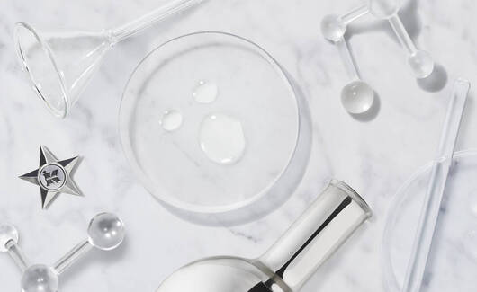 Alt-Text: Verschiedene Laborglaser und Werkzeuge auf einer marmorierten Oberflache, umgeben von Wassertropfen.