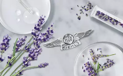 Lavendelbluten, Laborutensilien und das Kiehl's-Logo auf einem marmorierten Untergrund. Natur trifft Wissenschaft.