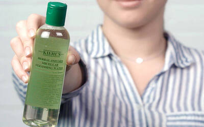 Eine Person halt eine Flasche mit Kiehl's Krauter-Mizellenreinigungswasser in der Hand.
