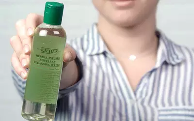 Eine Person halt eine Flasche mit Krauter-infundiertem micellarem Reinigungswasser von Kiehl's vor sich.