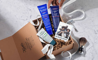 Eine Kiehl's Geschenkbox mit Hautpflegeprodukten, verbauter Rasierpinsel und einem Foto von zwei Personen.