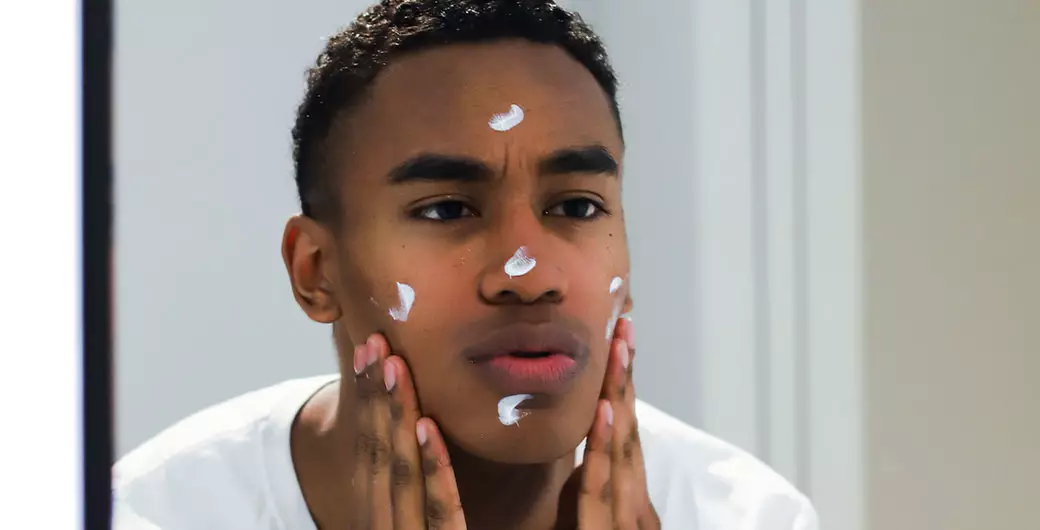 Mann cremt sich das Gesicht ein