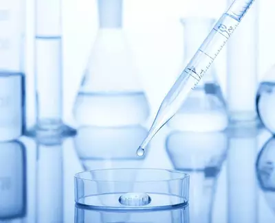 Une pipette droppant une goutte de liquide dans une coupelle, entouree de divers instruments de laboratoire.