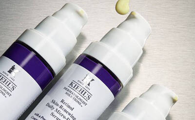 Drei Flaschen eines Retinol-Hautserums von Kiehl's, eine flussige Tropfen lauft von oben.
