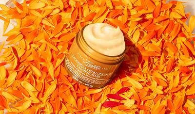 Gesichtsmaske mit Calendula Blattern im Hintergrund