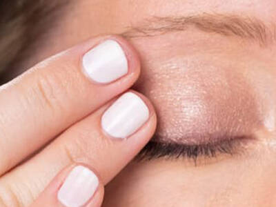 Frau schließt ihr Auge und versteckt Krahenfuße 