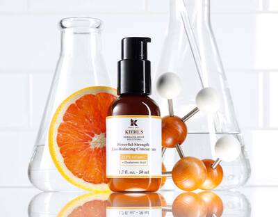 Flasche mit Kiehl's Liniensenkendem Konzentrat, umgeben von einem Orangenstuck und Wissenschaftsgeraten.
