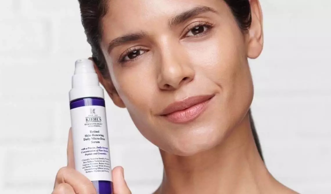 Gesicht einer Frau, die das Kiehl‘s Retinol Tagesserum in der Hand halt