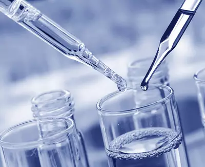 Close-up of two pipettes hovering over a glass beaker filled with liquid, with a soft blue tone.