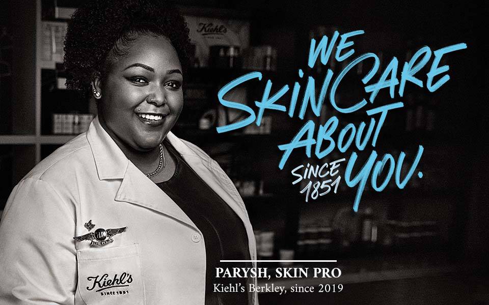 Ein Portrat einer lachelnden Frau in einem weißen Laborkittel vor einem Regal mit Hautpflegeprodukten, umgeben von einer grafischen Schriftzug "WE SKINCARE ABOUT YOU! SINCE 1951".